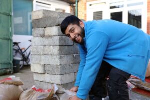 An apprentice lays bricks
