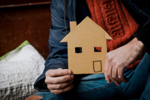 Image of homeless person holding a cardboard house